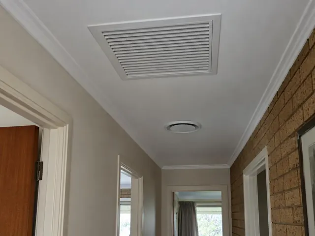 Ceiling return-air grille in a hallway with brick feature wall and doorframes in Hope Valley